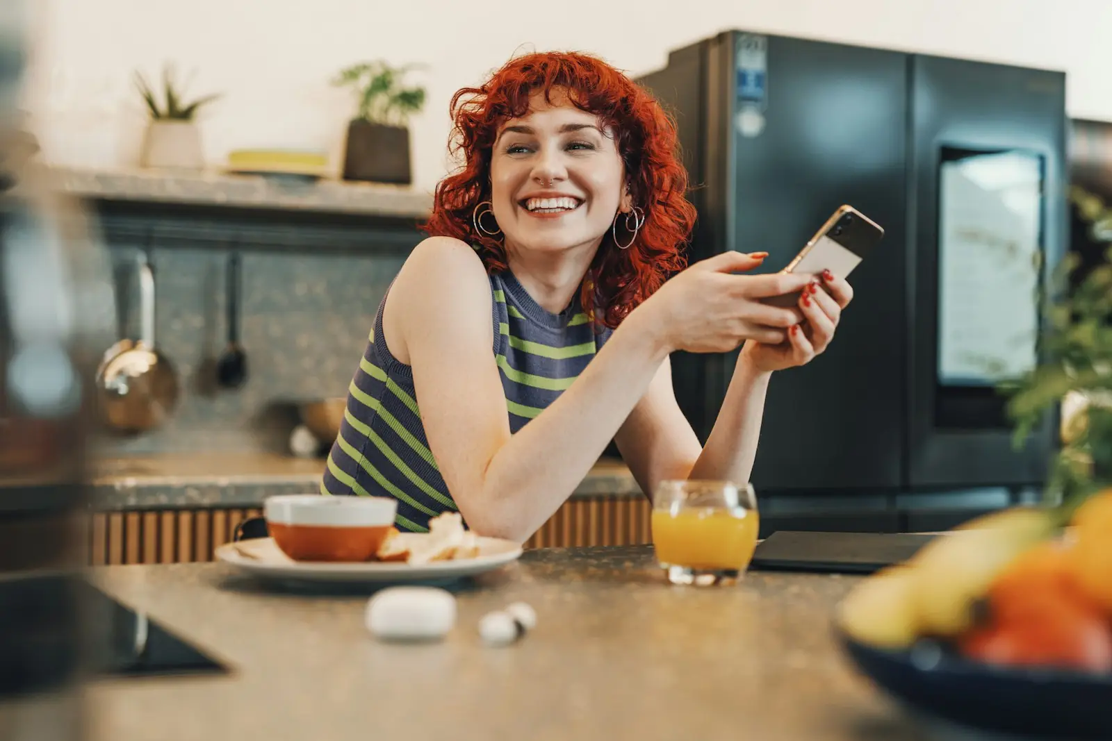 Mulher sorrindo com o celular na mão, na cozinha